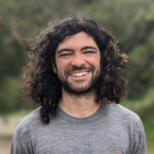 Gabriel Poesia wearing a gray shirt and smiling at the camera.